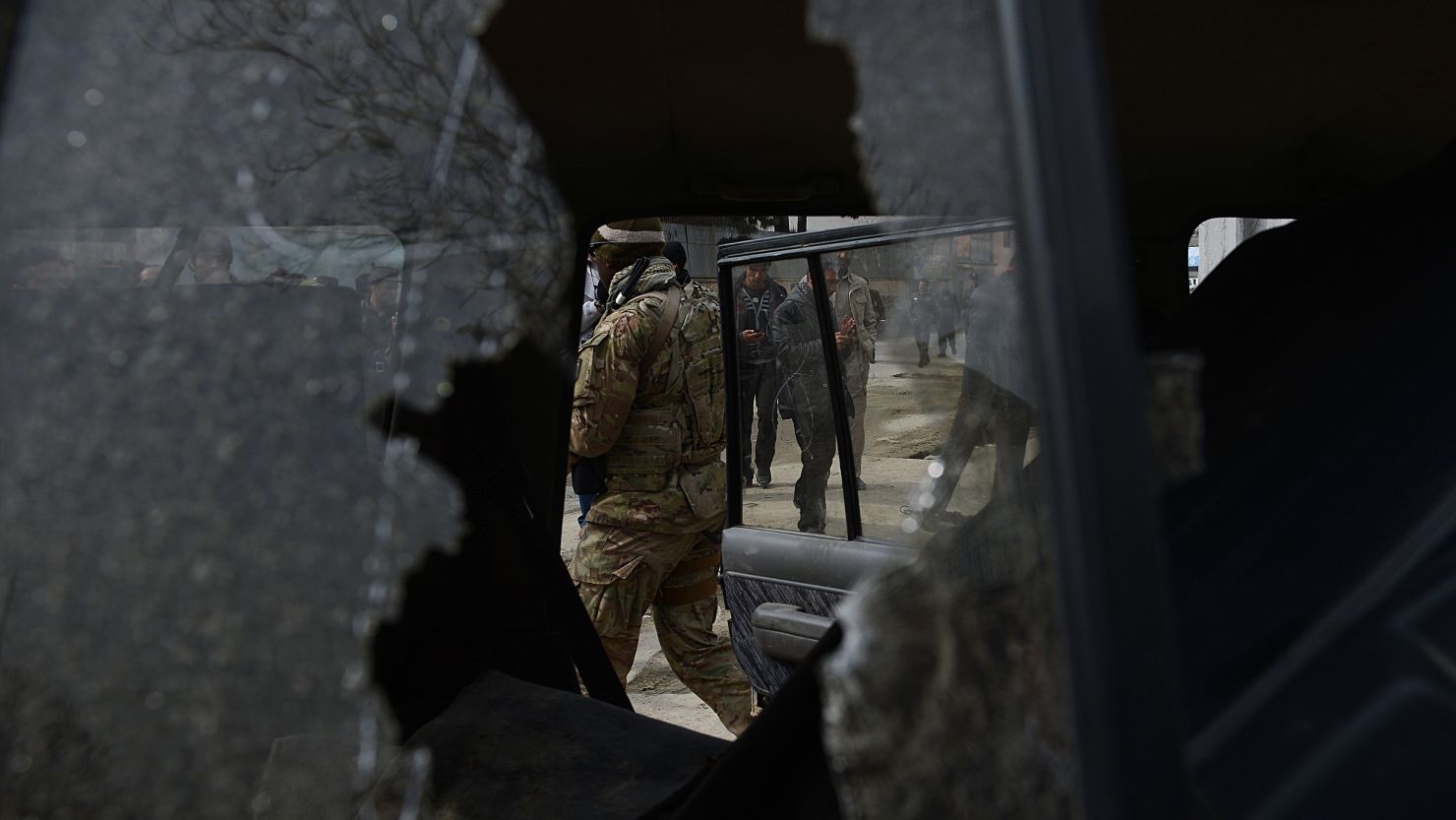 A US soldier and Afghan policemen are seen through the broken window of a suicide bombers' car in Kabul on February 24, 2013.