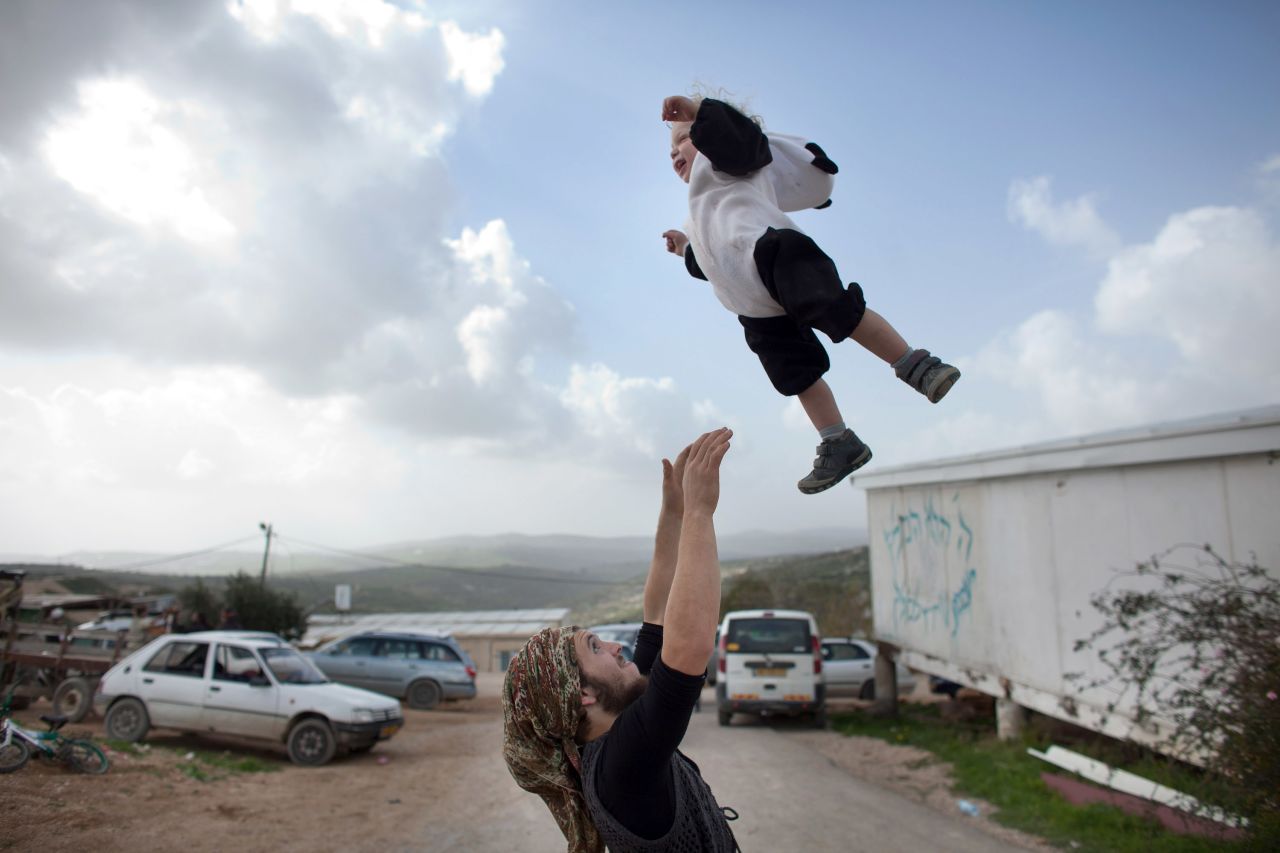  A Jewish settler plays with his baby at the settlement outpost of Havat Gilad, West Bank.