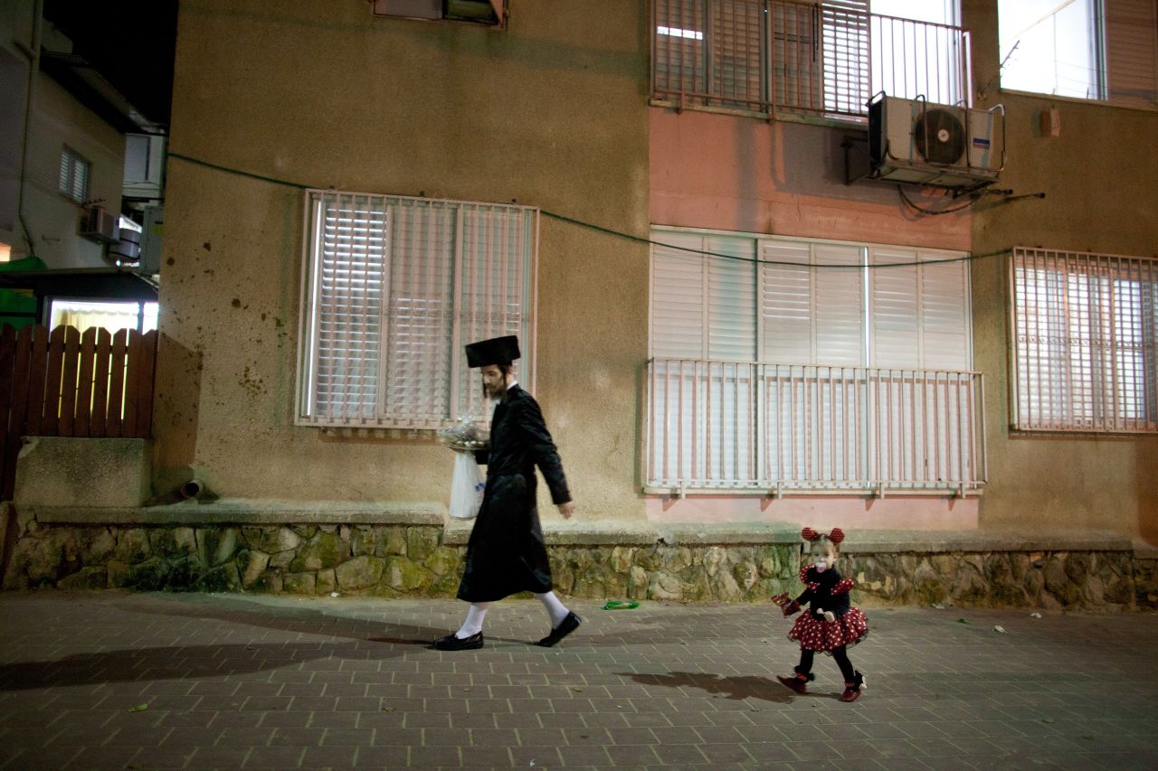 An Ultra-Orthodox Jew walks the street with his child as she wears a costume on February 23, 2013 in Bnei Brak, Israel. 