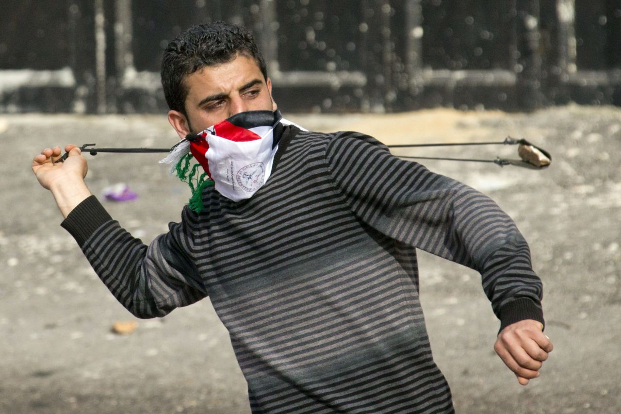 A Palestinian protestor uses a slingshot to throw stones towards Israeli security forces during clashes in the West Bank village of Saair on February 25, 2013 after the funeral of a Palestinian inmate who died in an Israeli prison.