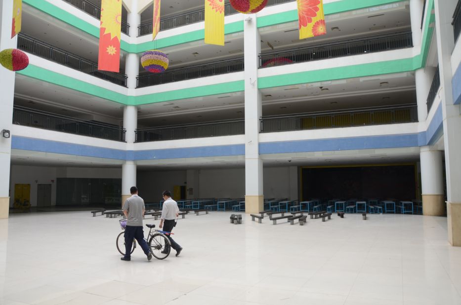 Two men walking through the empty mall in a space planned for restaurants.