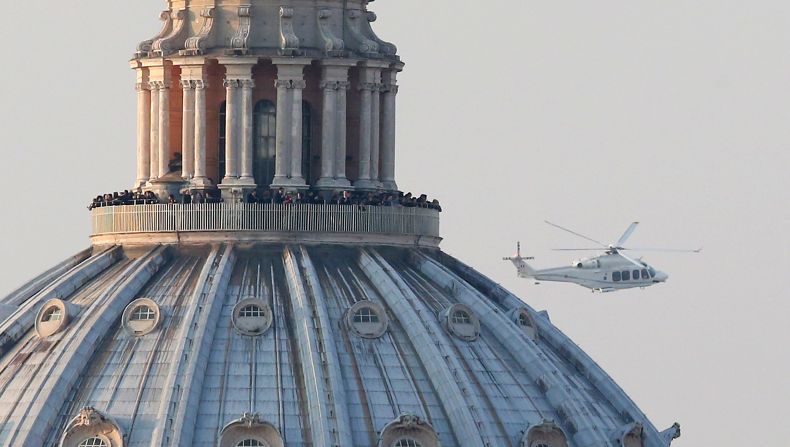 People crowd the gallery on top of St. Peter's Basilica as a helicopter carrying Pope Benedict XVI passes by on its way out of Vatican City.