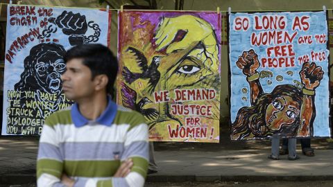 A demonstrator stands in front of posters during a protest rally in New Delhi calling for justice for women. 
