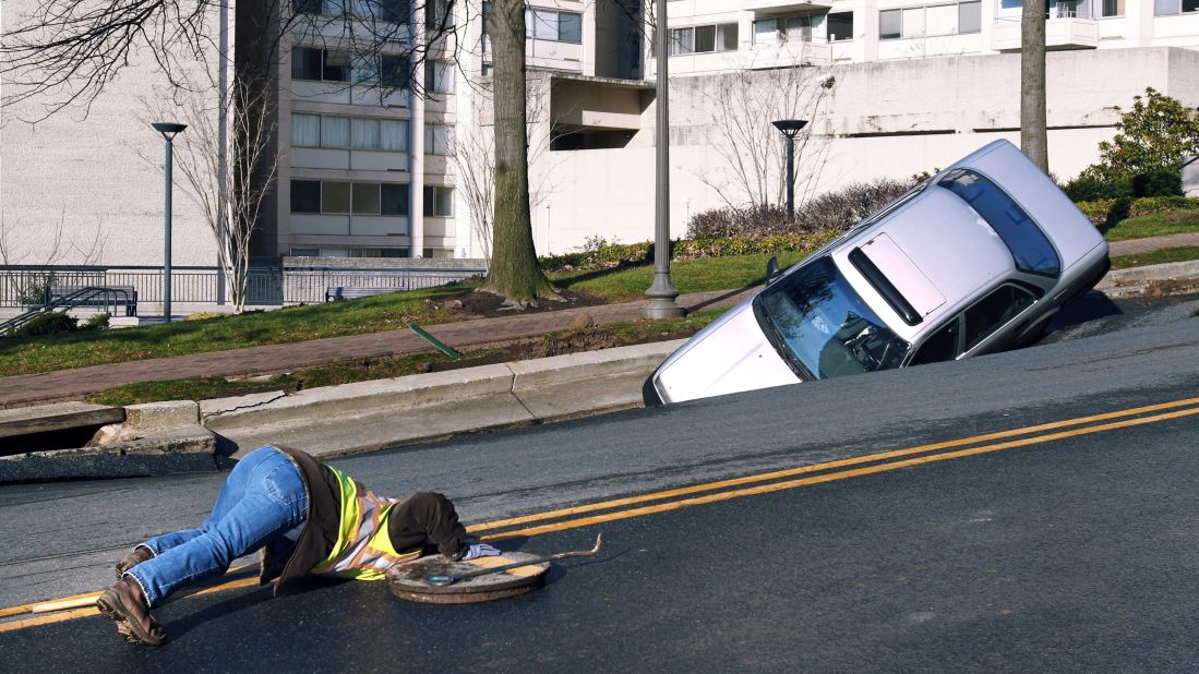 A utility worker examines the area around a sinkhole caused by a broken water main in Chevy Chase, Maryland, in December 2010.