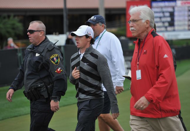 Flanked by officials and security, McIlroy makes a quick exit from the course at Palm Beach Gardens in Florida.