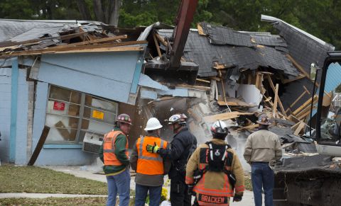 Workers watch the demolition of the house where a sinkhole opened three days before in Seffner, Florida, on March 3. Sinkholes caused by acidic groundwater corroding the limestone or carbonate rock underground are common in Florida, according to the Florida Department of Environmental Protection.  