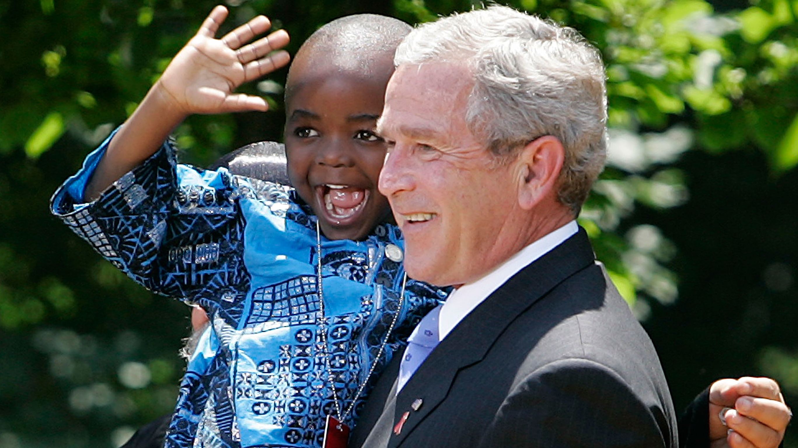 President George W. Bush holds up 4-year-old Baron Tantoh during a news conference on PEPFAR.