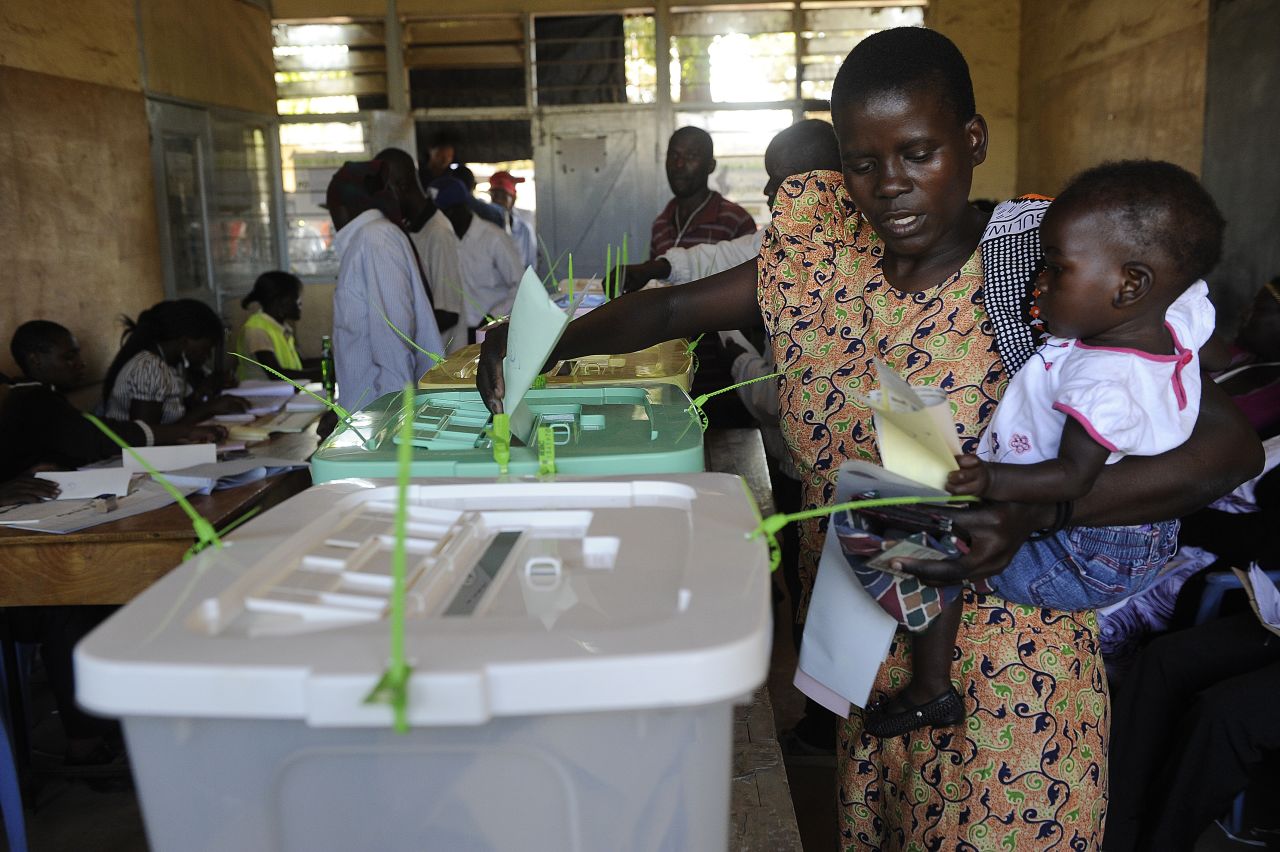 Kenyan women carrying her baby casts her ballot at a polling booth in the Mathare, in Nairobi on March 4, 2013 during the elections.