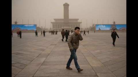 A man covers his face as he walks around Tiananmen Square during a sand storm in heavily polluted weather in Beijing on February 28.
