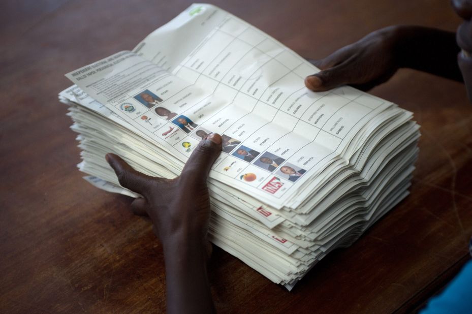 A voting assistant stacks ballot papers marked with a vote for presidential candidate Raila Odinga to an assistant at the Olympic Primary School in Kibera, Nairobi on March 4, 2013.