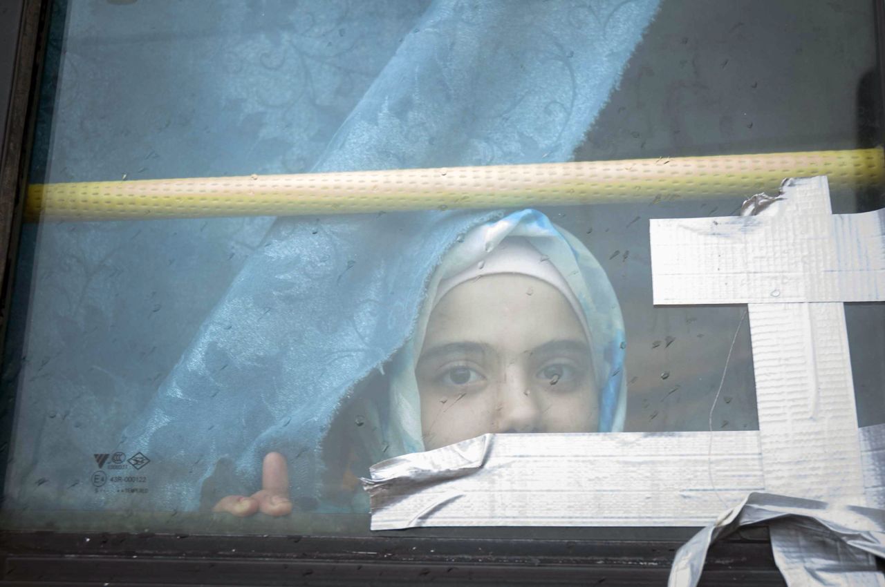 A Syrian girl looks through the window of a bus where she has lived with her family for the past eight months in February 2013.