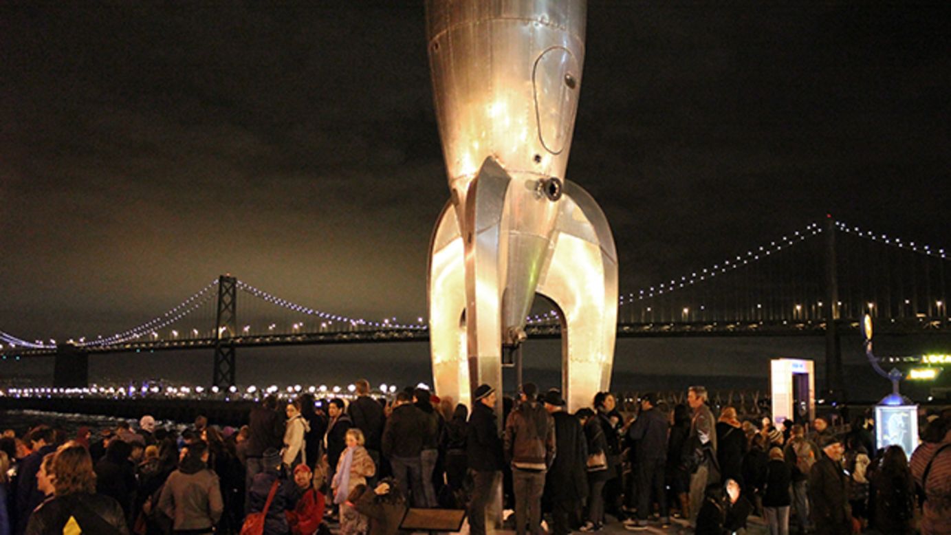 Another piece of public art, the Raygun Gothic Rocketship, is lit up in front of the Bay Bridge. 