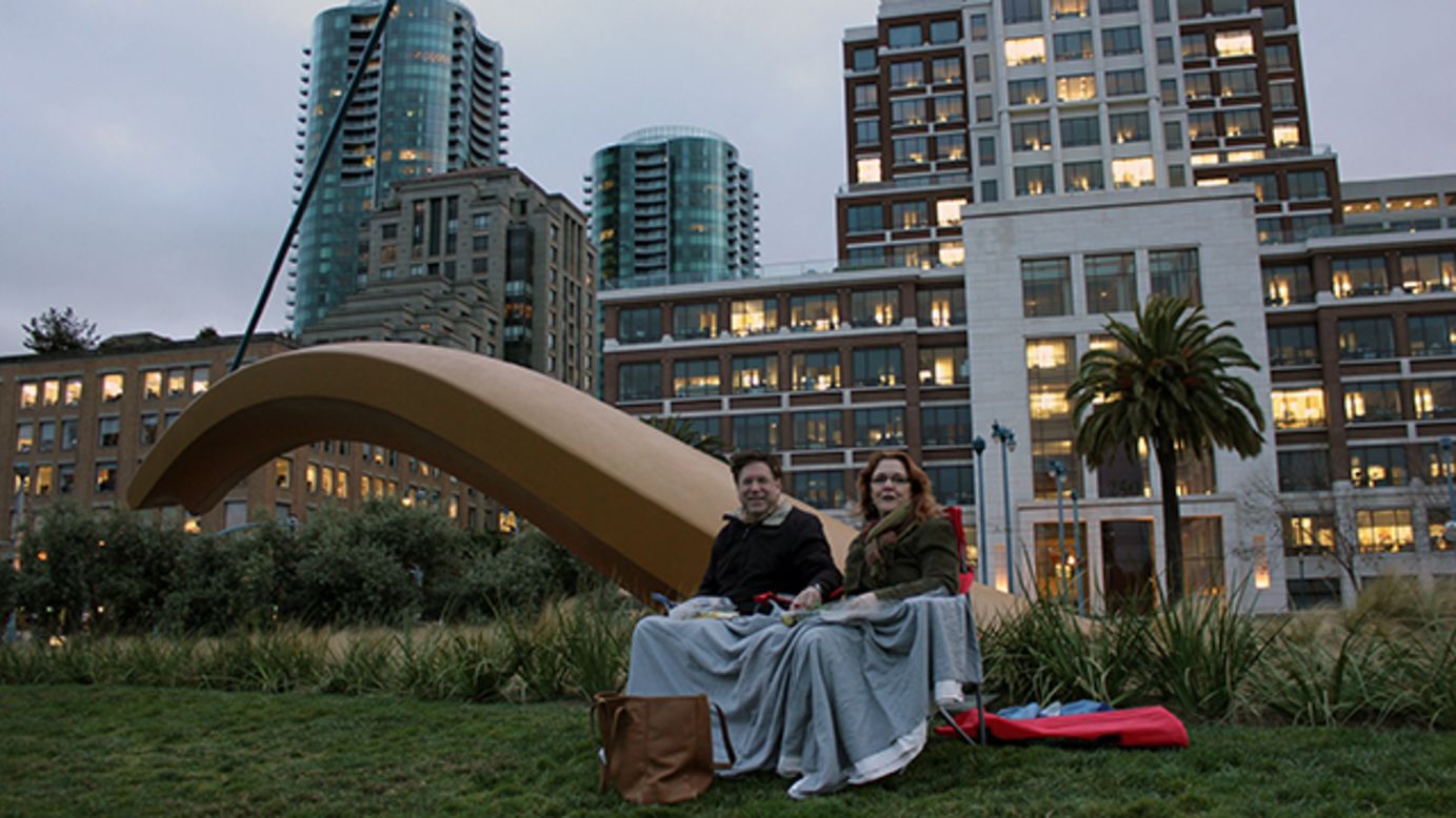 San Francisco residents cozy up with a picnic to watch the Bay Bridge light up. 
