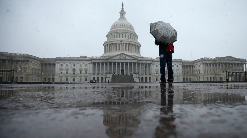 A tourist takes cover under an umbrella while snapping photos of the U.S. Capitol on March 6, in Washington.