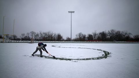 Hunter Gallagher uses a shovel to write a letter in his girlfriend's name in the snow on the football field at Catholic University on March 6 in Washington.