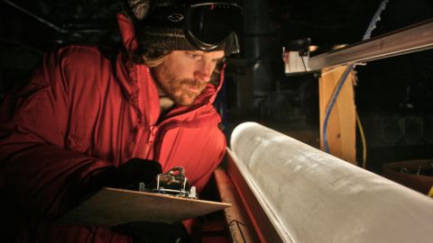 A scientist looks at an ice core from the West Antarctic Ice Sheet Divide coring site.