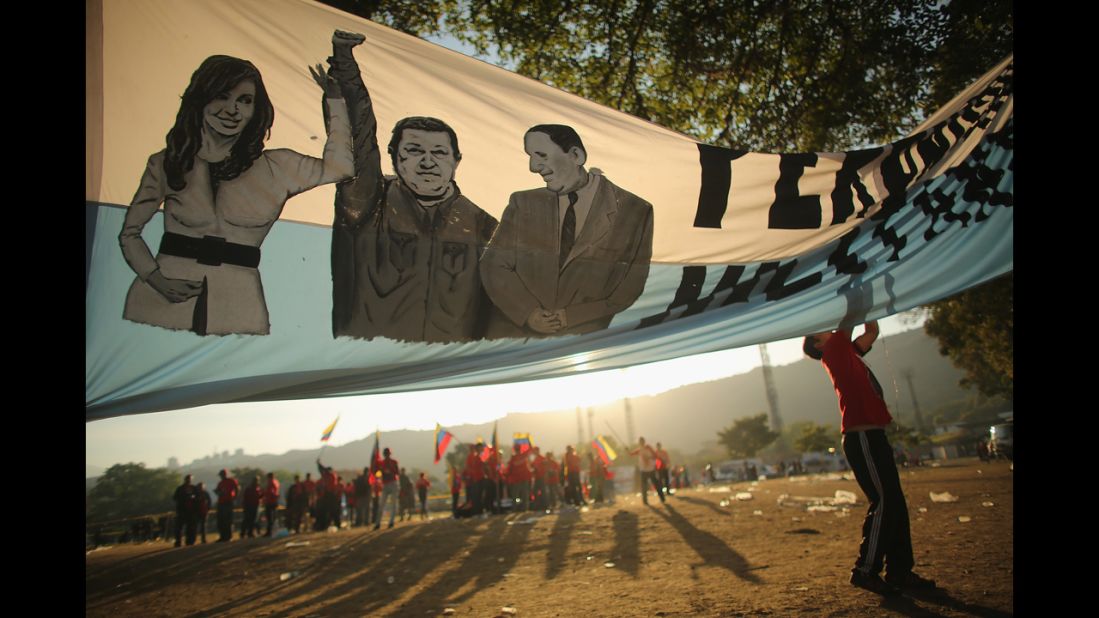 A man adjusts a banner before the start of Chavez's funeral outside the Military Academy.