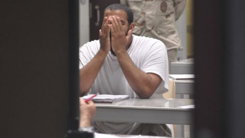 A detainee rubs his face while attending a 