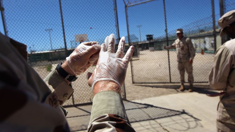A military guard puts on gloves before moving a detainee in September 2010.