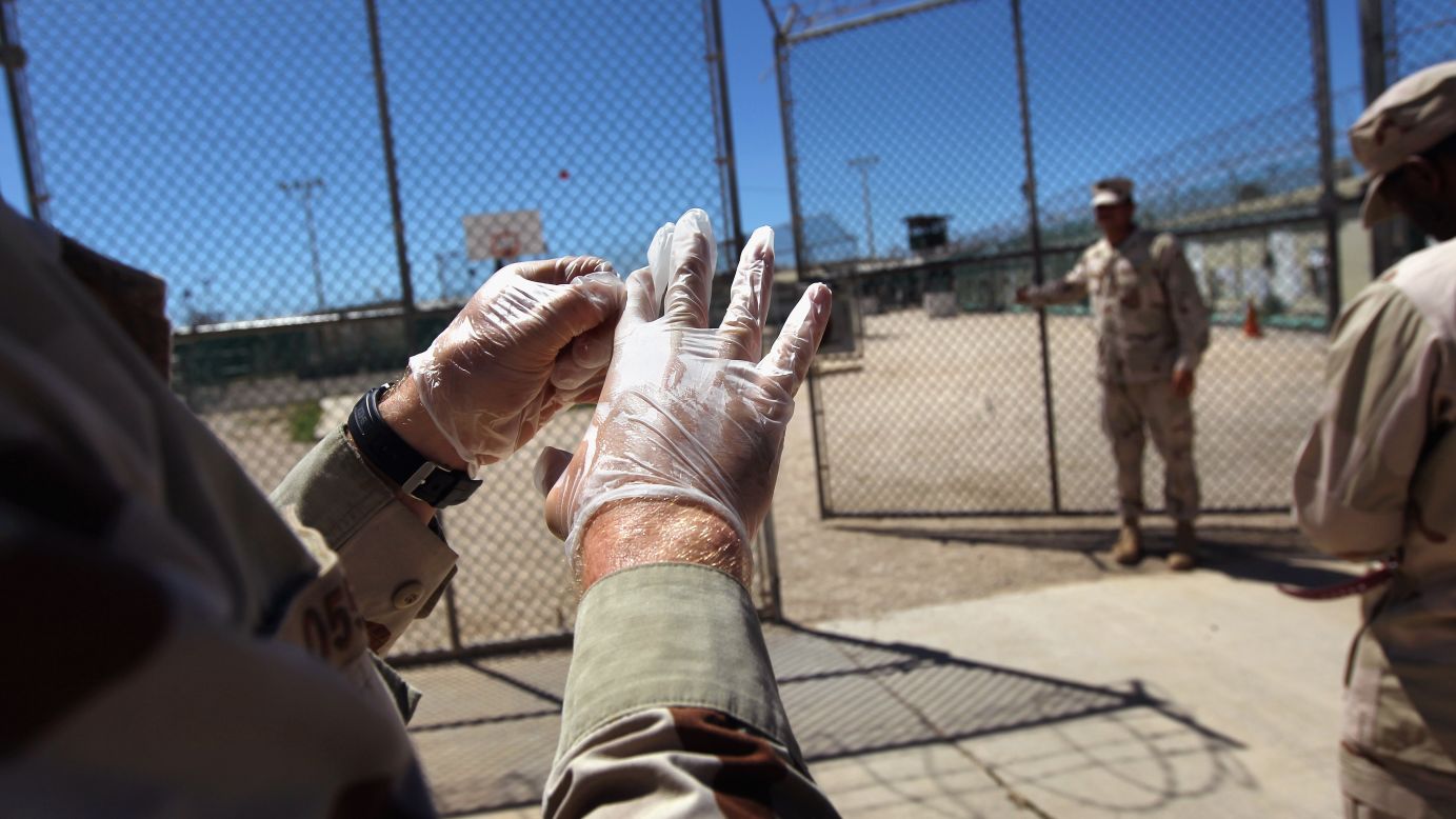A military guard puts on gloves before moving a detainee in September 2010.
