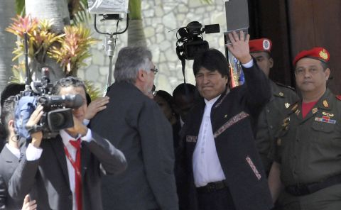 Bolivian President Evo Morales, center, waves next to former Paraguayan President Fernando Lugo outside of the funeral on March 8.