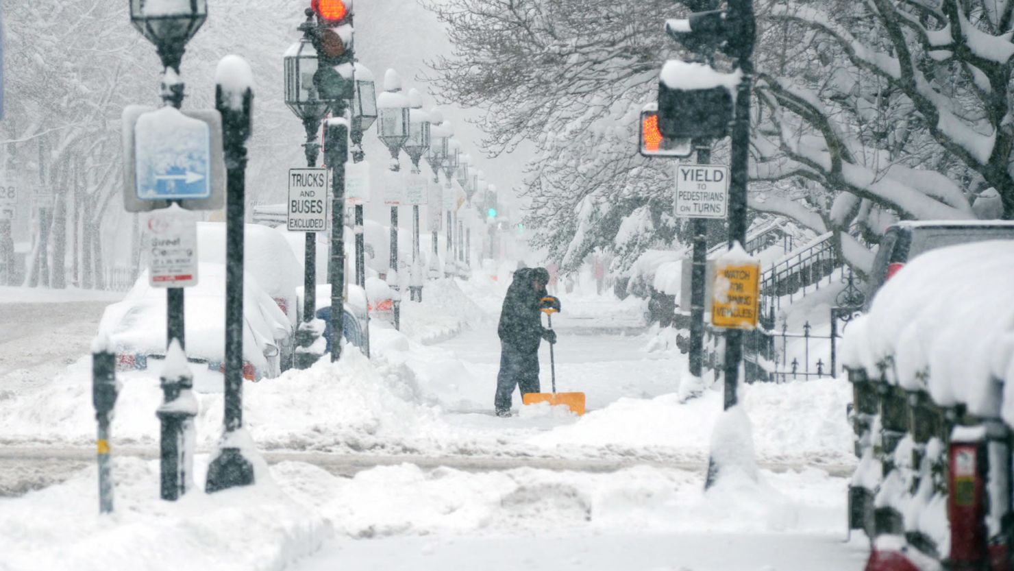 A man shovels snow on Boston's Commonwealth Avenue. Delays of 2.5 hours were reported at Boston's Logan Airport.
