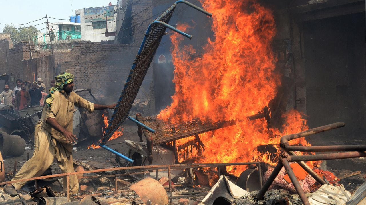 An angry Pakistani demonstrator torches Christian's belongings in Lahore during a protest over a blasphemy row.