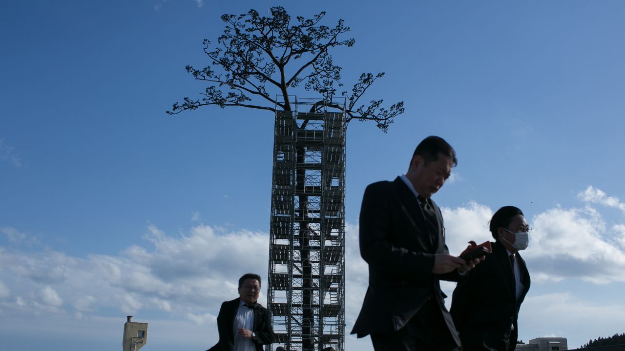 Visitors walk in front of a replica of the "miracle" pine tree on Sunday in Rikuzentakata. It was the last surviving pine in what was once a sprawling grove of more than 70,000, standing as a symbol of hope amid the devastation.