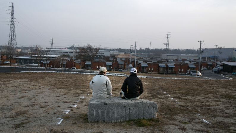 Men sit on a bench in front of a temporary housing shelter on Thursday, March 7, in Motomiya, Fukushima Prefecture. Thousands were displaced in the aftermath of the earthquake.