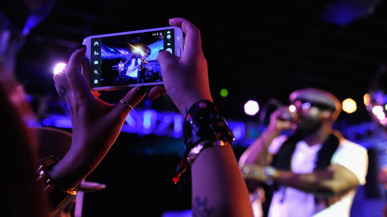 An attendee uses her mobile phone to snap a picture of The Roots' show on March 9.