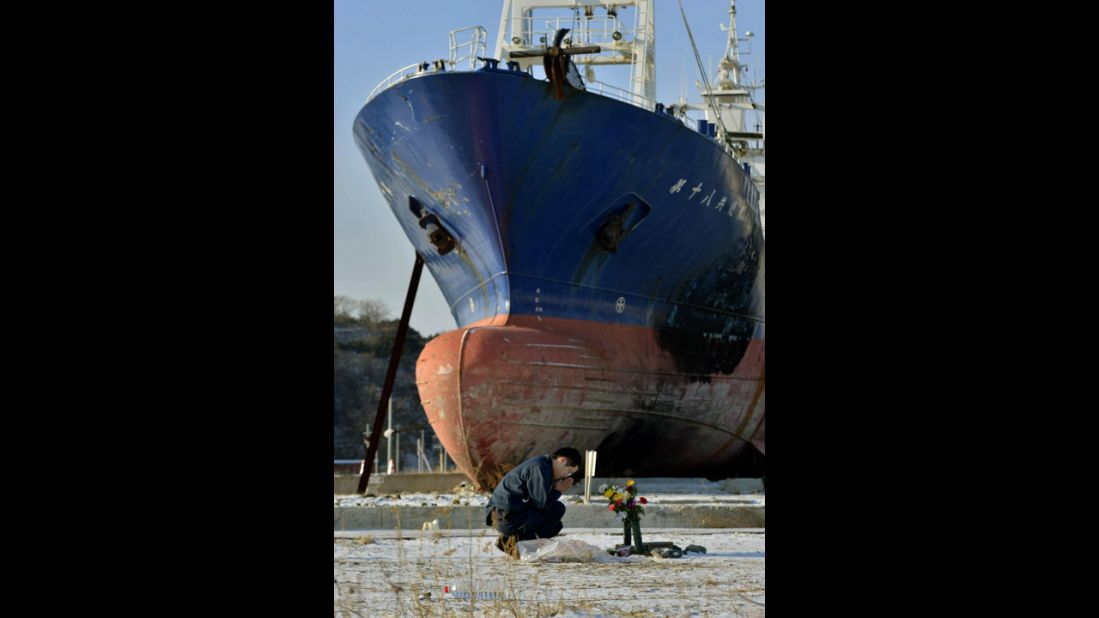 A man mourns on Monday in front of a ship brought ashore by the 2011 tsunami in Kesennuma, Japan.