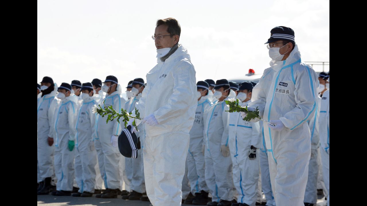 Police officers offer chrysanthemum flowers for tsunami victims in Namie on Monday after their search for remains of those still missing, two years after the disaster.
