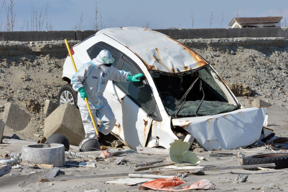 A police officer searches for remains in a wrecked vehicle at a beach in Namie, Japan, near the stricken Fukushima Dai-ichi nuclear plant, on Monday, March 11, the second anniversary of the tsunami. Two years ago, a magnitude-9.0 earthquake unleashed a wall of water that killed nearly 16,000 people in northeast Japan and sparked the world's worst nuclear crisis in 25 years.