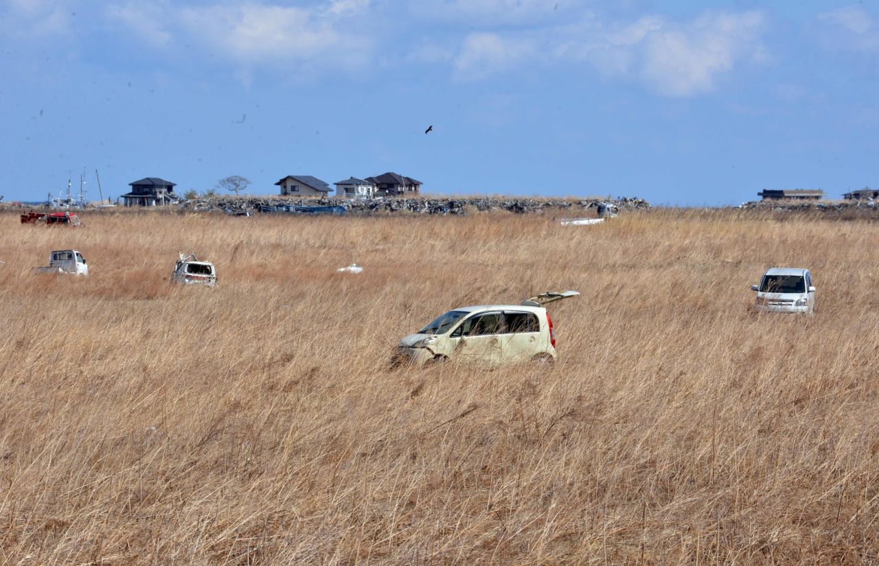 Vehicles that were abandoned two years ago sit in a field of reeds in Namie on Monday.