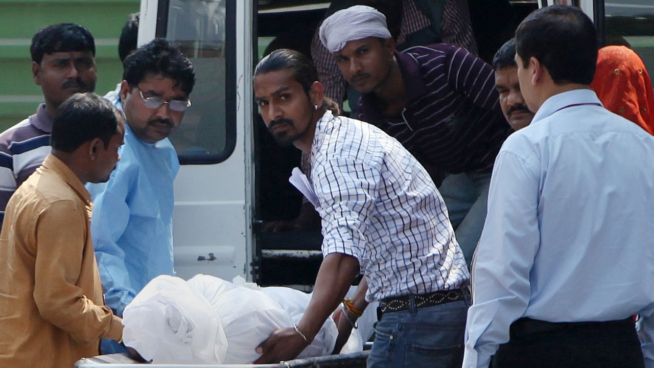 Hospital staff and family members of Ram Singh transport his body into an ambulance on Tuesday.