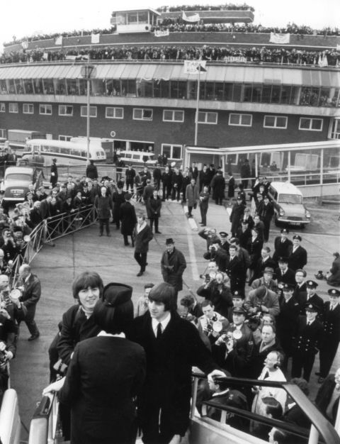The Beatles board their Pan Am jet at Heathrow airport for their first U.S. tour in February 1964, accompanied by Freeman. They were waved off by 4,000 screaming fans.
