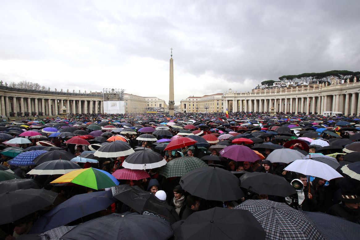 People shelter under umbrellas while they wait in St. Peter's Square for news on the election of a new pope on March 13 in Vatican City.