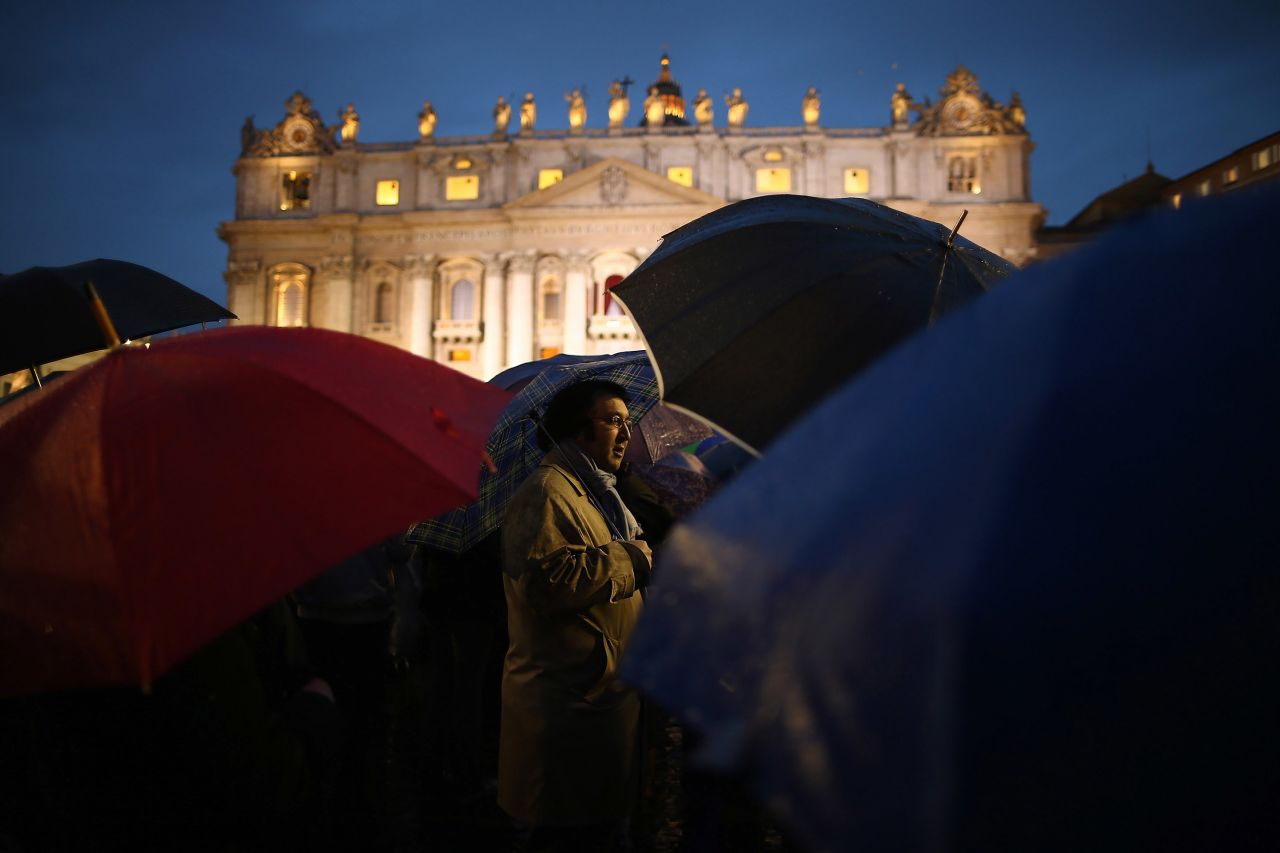 People shield themselves from the rain in St. Peter's Square after the election of the new pope.