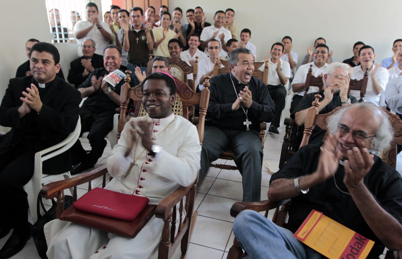 Fortunatus Nwachukwu, in white, the Vatican's ambassador to Nicaragua, applauds as he watches a local television station announcing the new pope with others in Managua, Nicaragua.