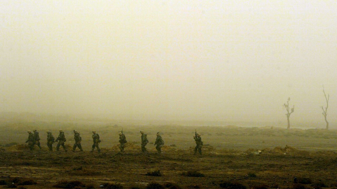 Marines walk single-file through the desolate landscape in Nasiriyah on March 26, 2003. As night falls on the city, the troops are on alert for a counterattack.