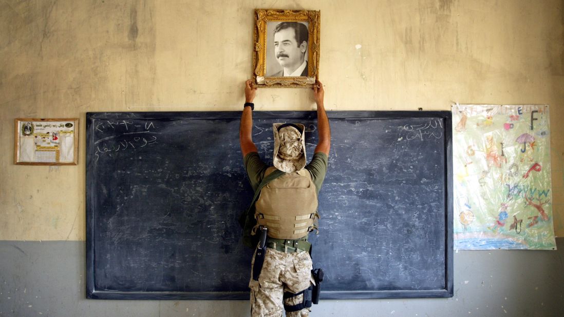 A U.S. Marine pulls down a picture of Saddam Hussein at a school in Al-Kut on April 16, 2003.