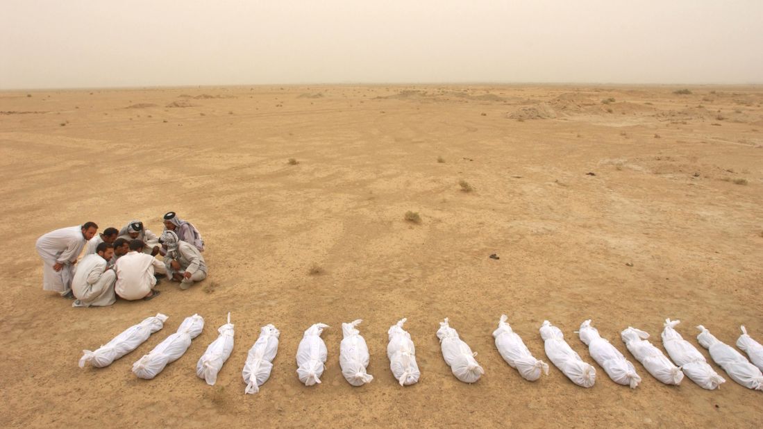 Iraqi men check a list near the remains of bodies excavated from a mass grave on the outskirts of Al Musayyib on May 31, 2003. Locals said they uncovered the remains of hundreds of Shiite Muslims allegedly executed by Saddam Hussein's regime after their uprising following the 1991 Gulf War.