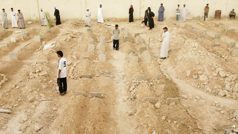 Iraqis look at rows of graves at an overflowing cemetery built in a soccer arena in Fallujah on May 3, 2004.