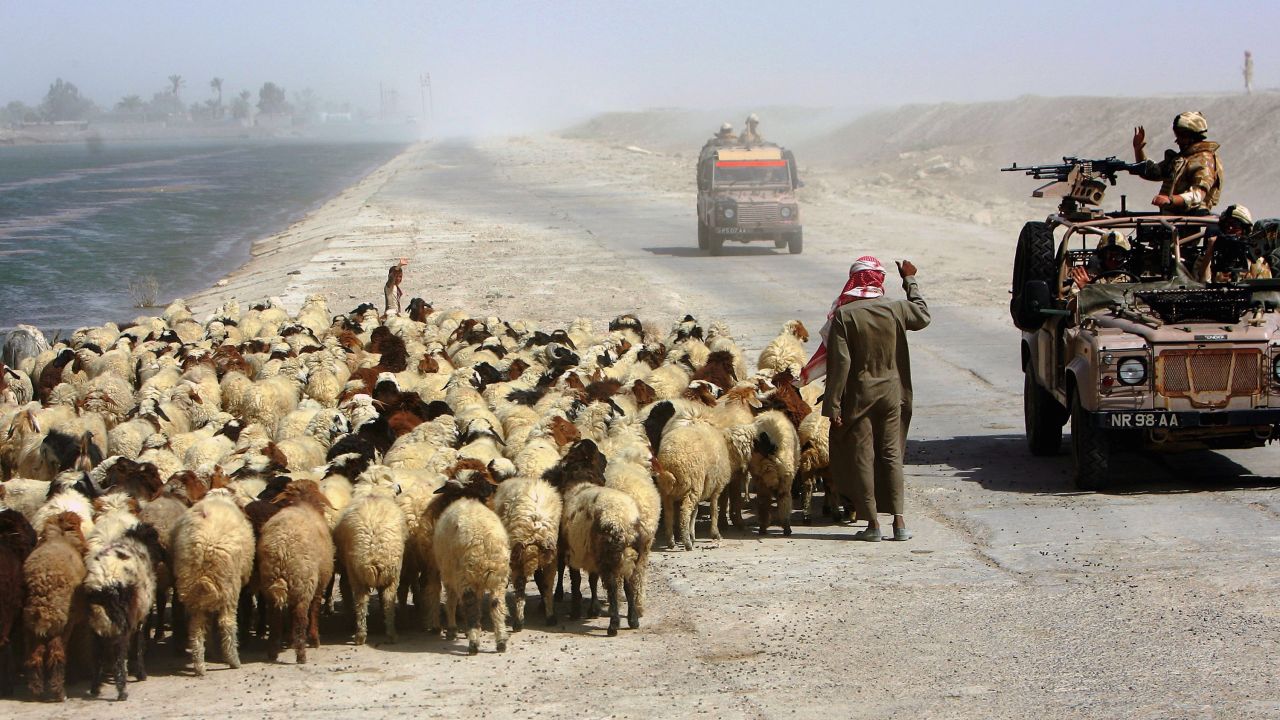A British Royal Air Force gunner waves to a goat herder during a patrol of northern Basra province on July 26, 2006.