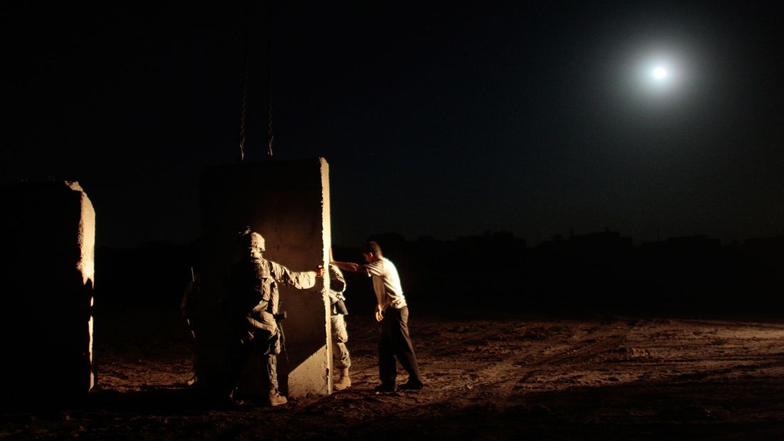 U.S. soldiers and an Iraqi contractor build a concrete wall between Sunni and Shiite areas of the south Dora neighborhood of Bagdhad in the early hours of July 4, 2007.