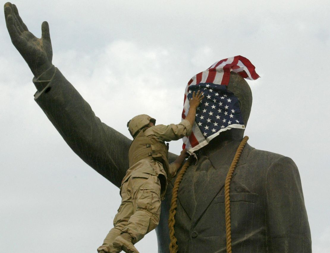 A US Marine covers the face of Saddam Hussein's statue with the US flag in Baghdad on 09 April 2003.