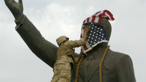 A US Marine covers the face of Saddam Hussein's statue with the US flag in Baghdad on 09 April 2003.