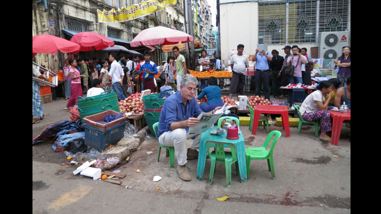 Anthony Bourdain reads the paper next to a local market in Yangon, Myanmar.