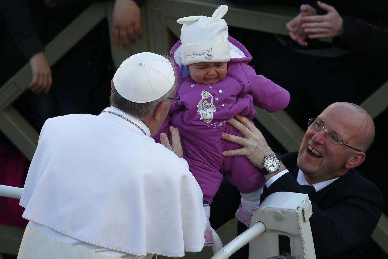 Francis greets a baby in St. Peter's Square. He obliged whenever the faithful held up children for him to kiss.