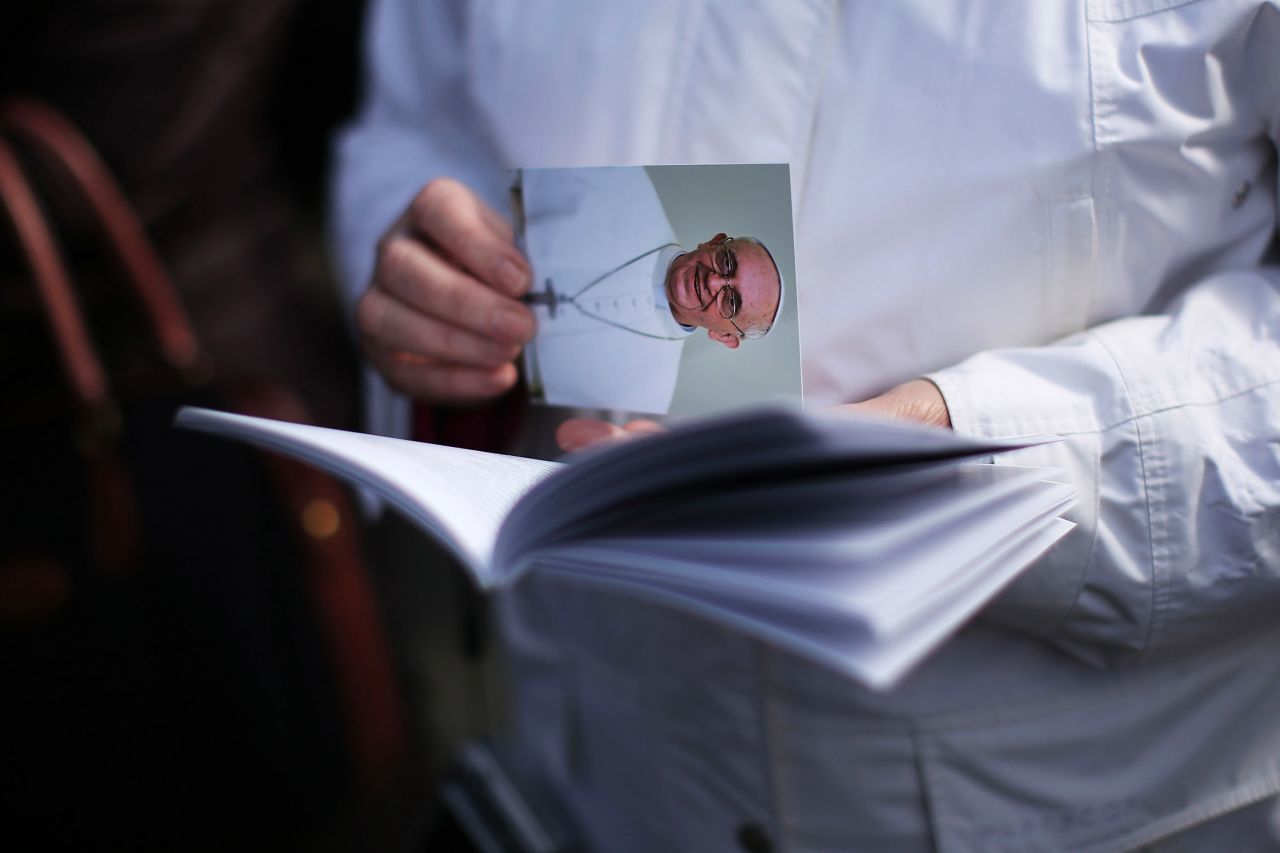  A woman holds a card with Francis' picture during the Mass.